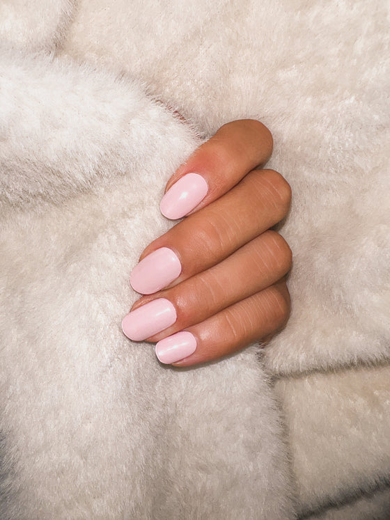 hand with pink pastel gel nail stickers while holding whit fur coat 
